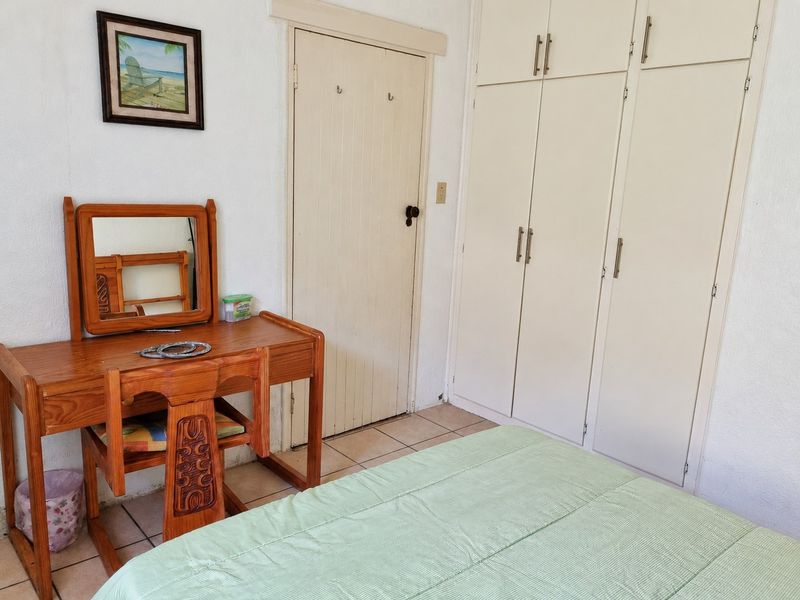 A functional bedroom featuring built-in cupboards and tiled flooring, offering a neutral base for potential cosmetic updates.