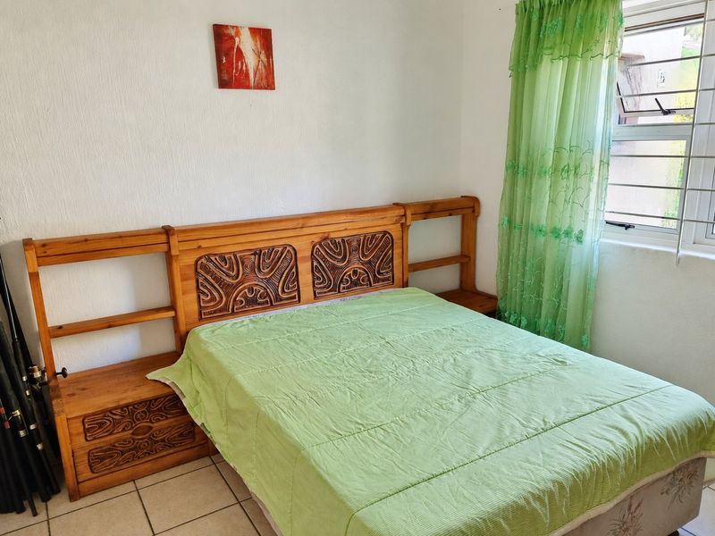 A functional bedroom featuring tiled flooring and a window fitted with security bars.