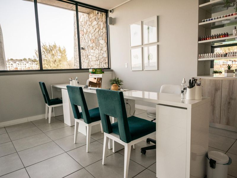 A well-lit commercial space featuring large windows, tiled flooring, and built-in shelving, currently configured as a professional nail salon.