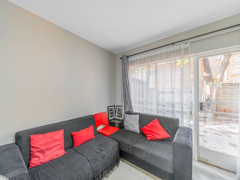 A living room area featuring tiled flooring and a glass sliding door providing access to the exterior.