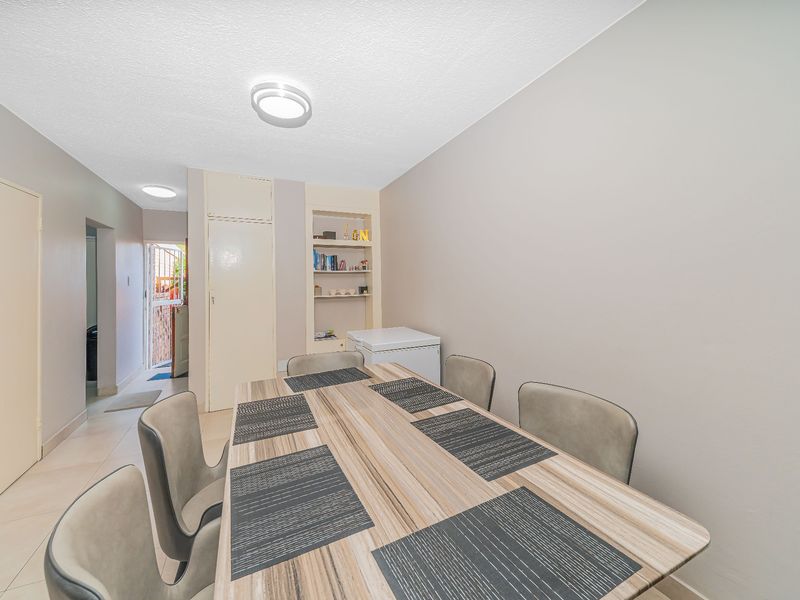 A functional dining area featuring tiled flooring, built-in shelving, and direct access to the exterior through a hallway.