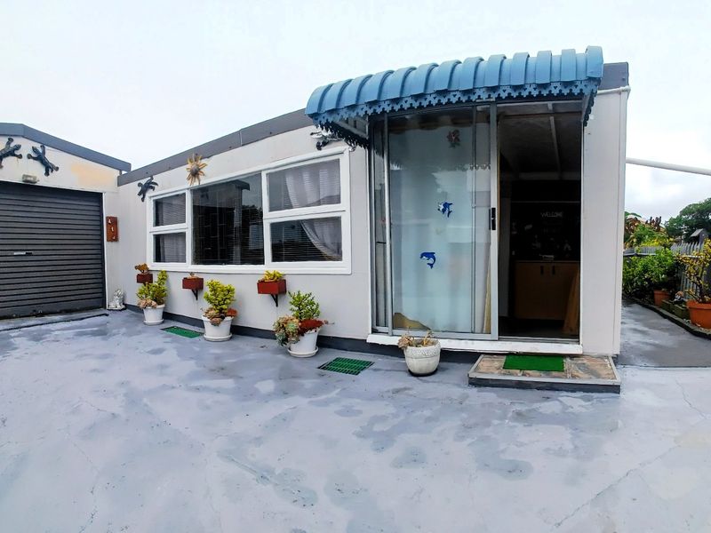 Front exterior view of the property featuring a garage with a roller shutter door, a sliding glass entrance, and a concrete driveway.