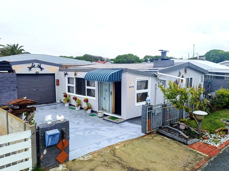 Front elevation of a single-story house featuring a garage, paved driveway, and a covered entrance with a blue awning.