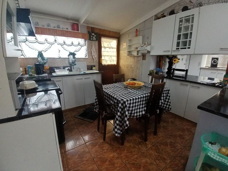 A functional kitchen featuring white cabinetry, dark granite countertops, tiled flooring, and an integrated extractor fan, providing a practical workspace for daily cooking.