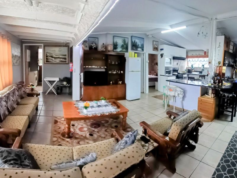 Spacious open-plan living area featuring tiled floors, exposed beam ceilings, and a functional kitchen with built-in cabinetry and an island.