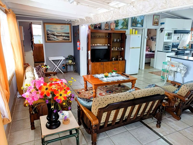 Open plan living area featuring tiled floors and exposed beam ceilings, seamlessly connecting to a functional kitchen space with built-in cabinetry.
