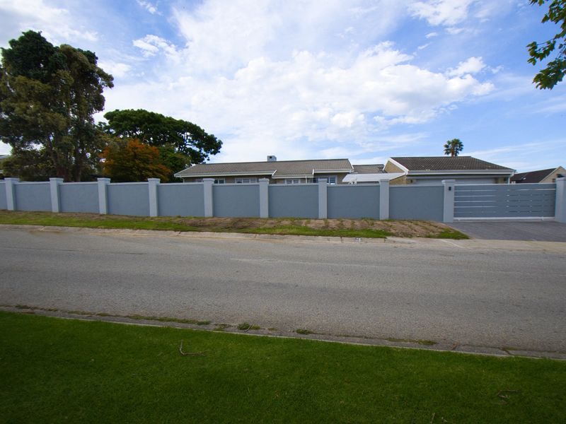 Street view of the property featuring a secure perimeter wall, gated driveway entrance, and tiled roof structure.