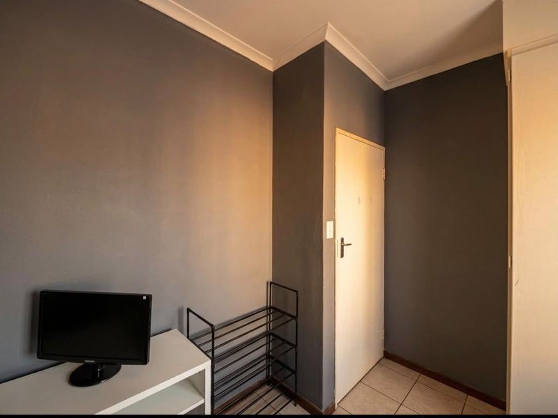 A simple hallway area featuring tiled flooring and neutral grey walls, providing a clean and functional transition space within the apartment.