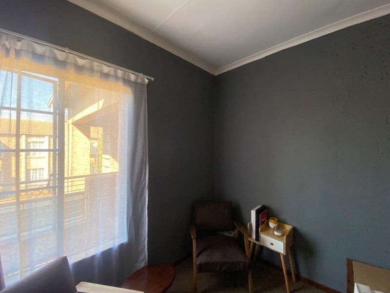 A bedroom featuring dark grey walls, a sliding window with sheer curtains, and cove cornicing.