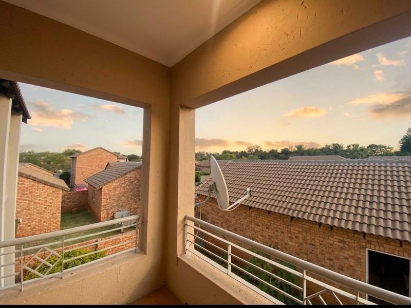 A covered balcony area featuring a metal balustrade with views over the surrounding residential complex.