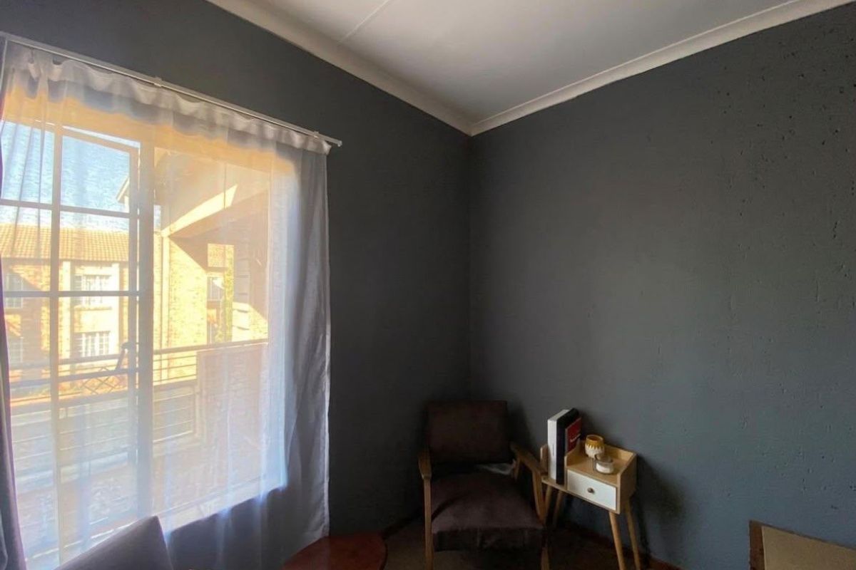 A bedroom featuring dark grey walls, a sliding window with sheer curtains, and cove cornicing.