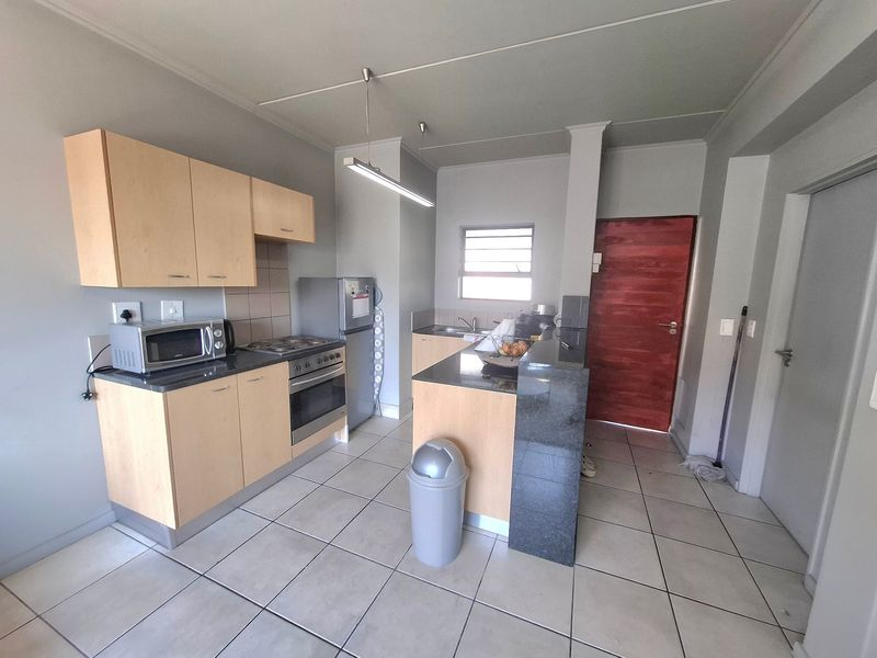 Functional kitchen featuring light wood cabinetry, stone countertops, a breakfast bar, and tiled flooring, providing a practical layout for daily cooking and dining.