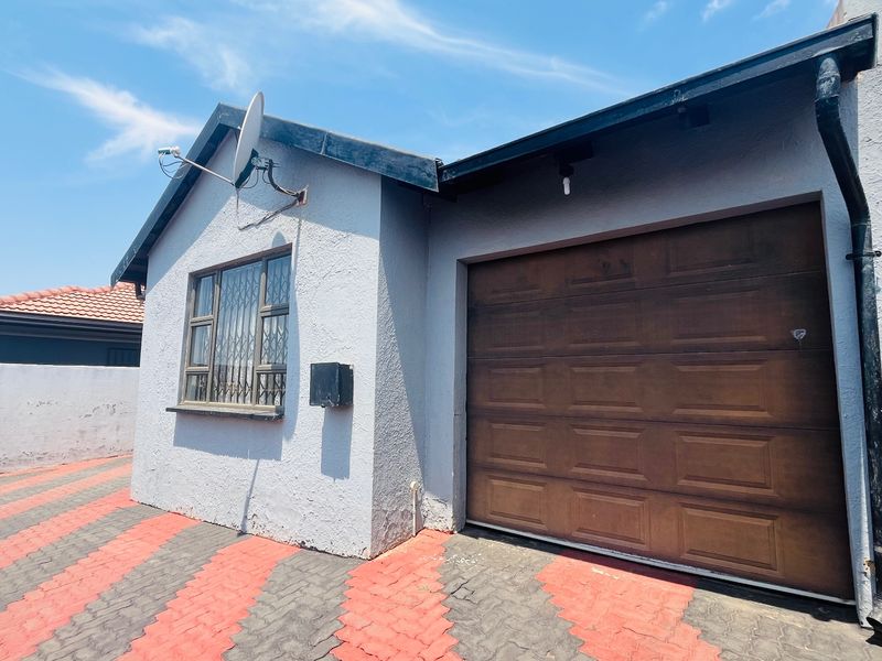 Front exterior view of the property featuring a single garage with a brown sectional door and a paved driveway.