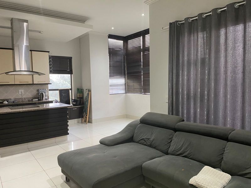 Open plan living area featuring a modern kitchen with granite countertops, stainless steel extractor fan, and tiled flooring throughout.