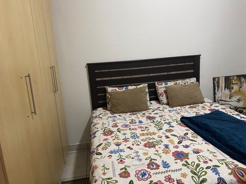 A functional bedroom featuring a built-in wardrobe and tiled flooring, providing a practical and neutral space for rest.