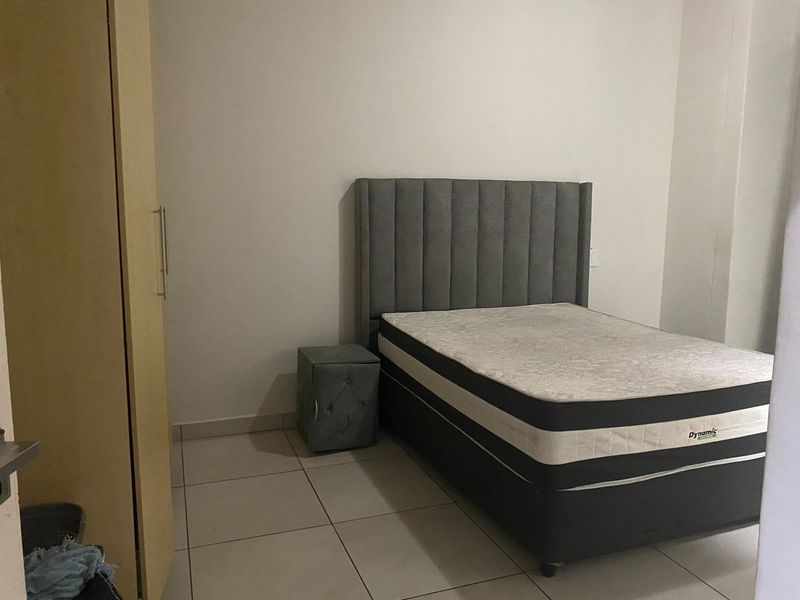 A bedroom featuring tiled flooring and a built-in wardrobe, providing a functional and neutral space.