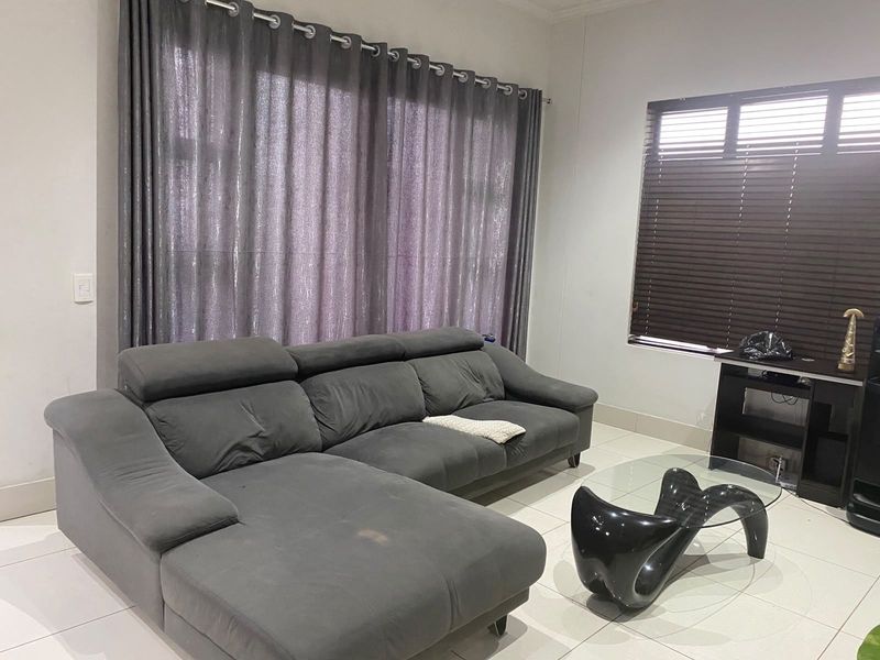 A living room featuring tiled flooring, large window with curtain tracks, and venetian blinds, providing a neutral base for interior design.