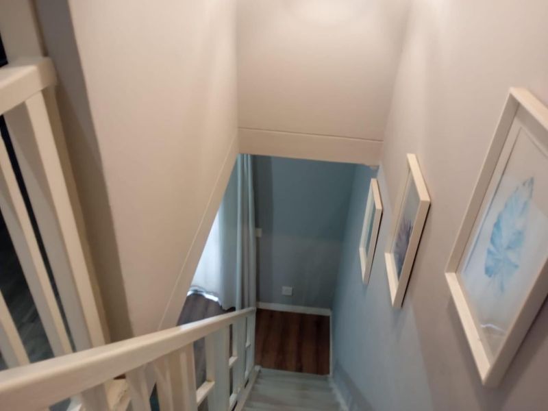A view looking down a staircase with a white balustrade and laminate flooring leading to a lower level.