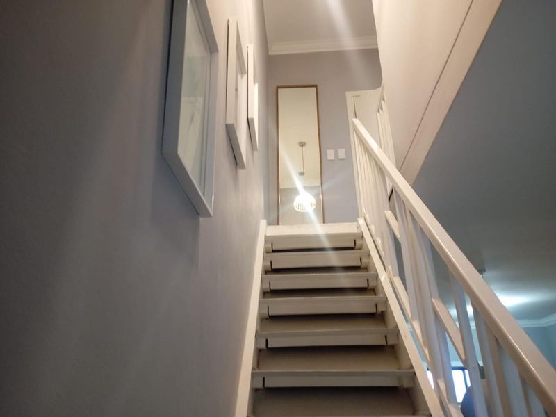 A bright, well-maintained staircase featuring a white wooden balustrade and neutral wall finishes, leading to an upper landing area.