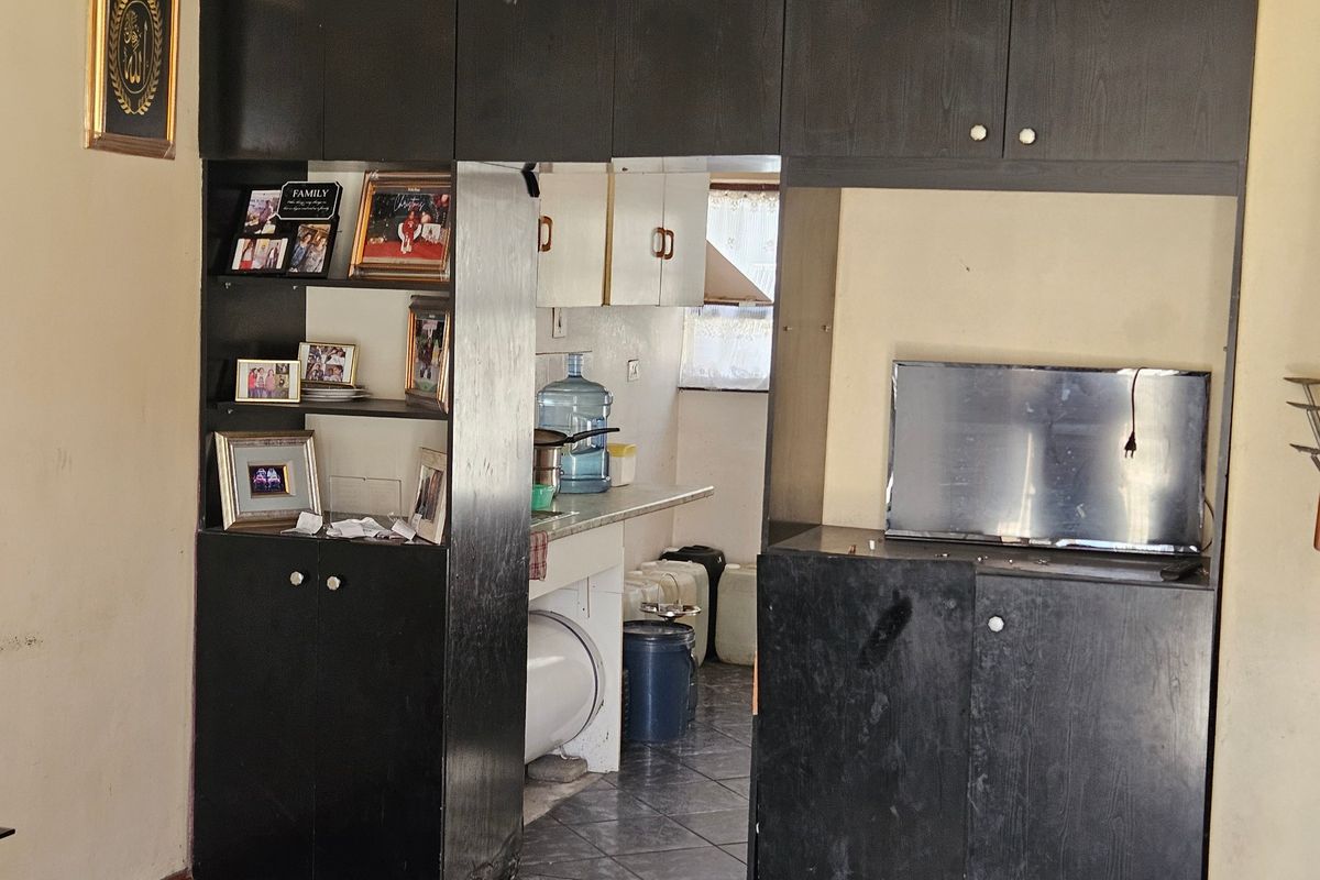 A kitchen area featuring dark built-in cabinetry and tiled flooring, offering functional storage space with potential for cosmetic updates.