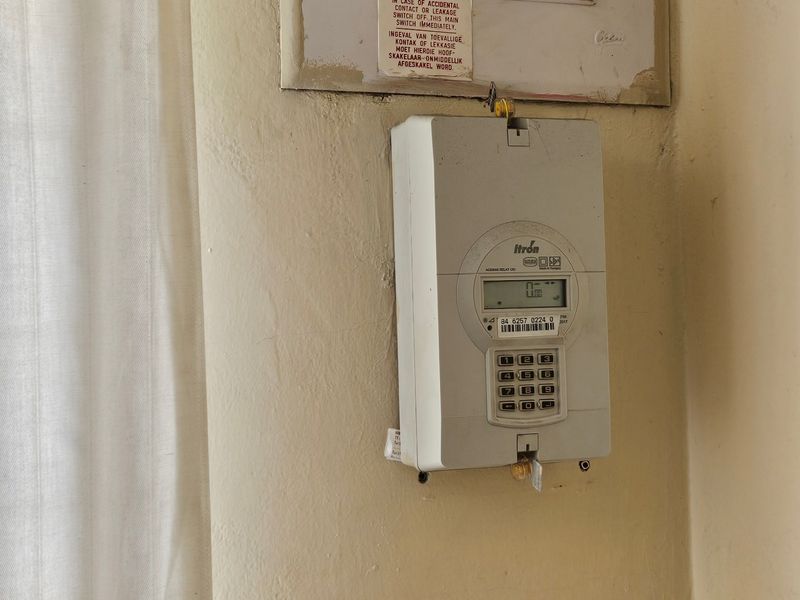 Wall-mounted electrical distribution board and prepaid electricity meter unit located in an interior utility area.
