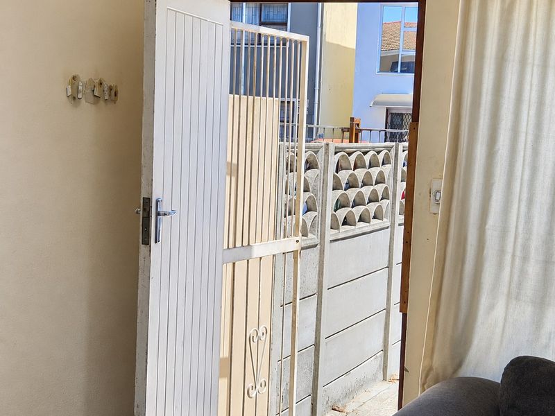An interior entry area featuring a security gate, tiled flooring, and direct access to an outdoor space with a precast concrete boundary wall.