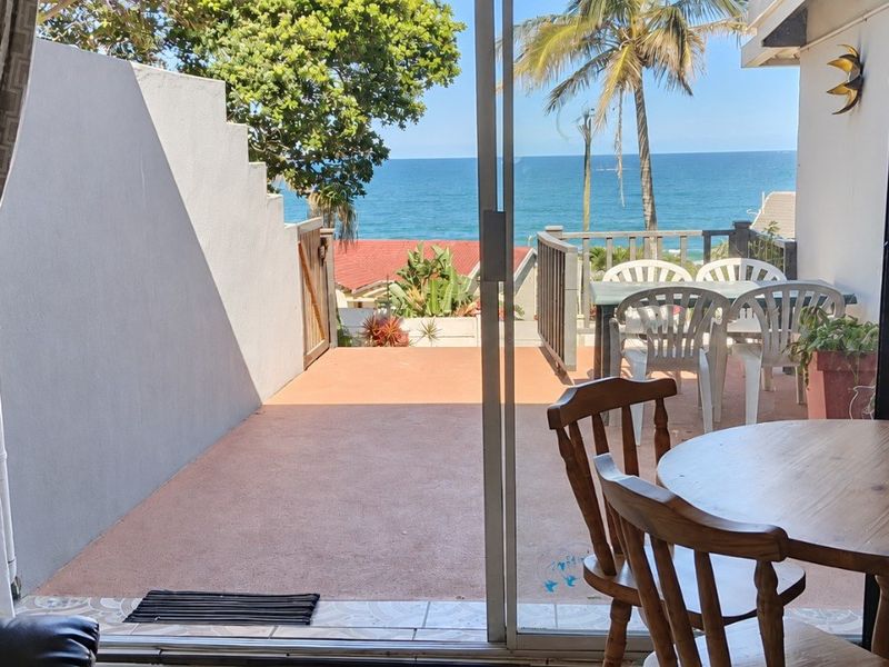 A covered patio area featuring sliding glass doors, concrete flooring, and a scenic ocean view, providing a seamless transition to outdoor living space.