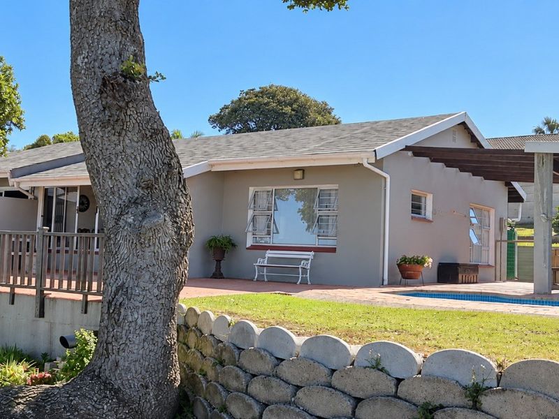 Rear exterior view featuring a swimming pool, covered patio area with a timber pergola, and a landscaped garden with a retaining wall.
