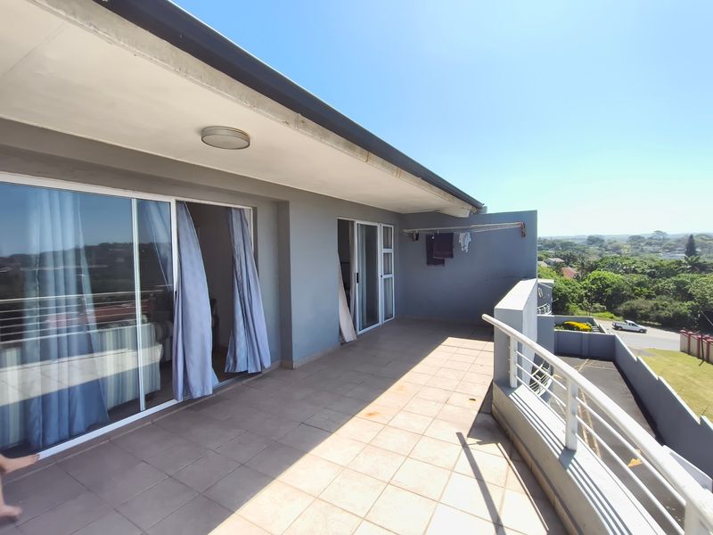 Spacious balcony featuring tiled flooring, metal balustrades, and sliding glass door access, offering an open outdoor area with elevated views.
