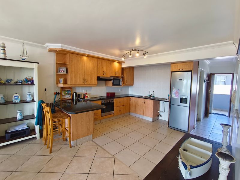 A functional kitchen featuring wooden cabinetry, granite countertops, built-in appliances, and tiled flooring, offering a practical layout with an integrated breakfast bar.