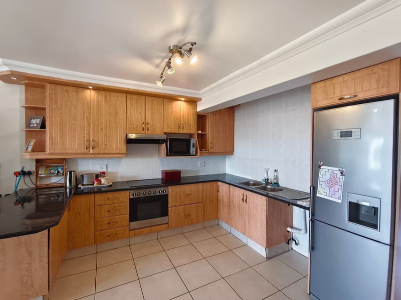 A functional kitchen featuring wooden cabinetry, granite countertops, built-in appliances, and tiled flooring, offering a classic layout with ample storage space.