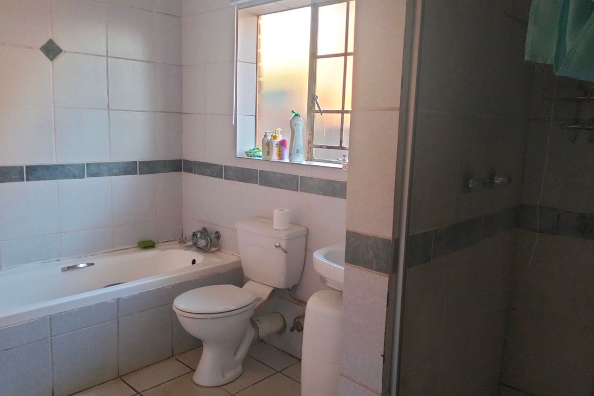 A functional bathroom featuring a bathtub, toilet, pedestal basin, and a separate shower enclosure with tiled finishes throughout.