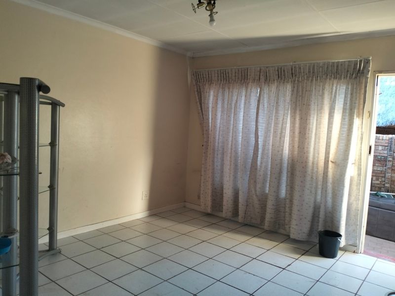 An empty living room featuring tiled flooring and a sliding glass door providing access to the exterior.