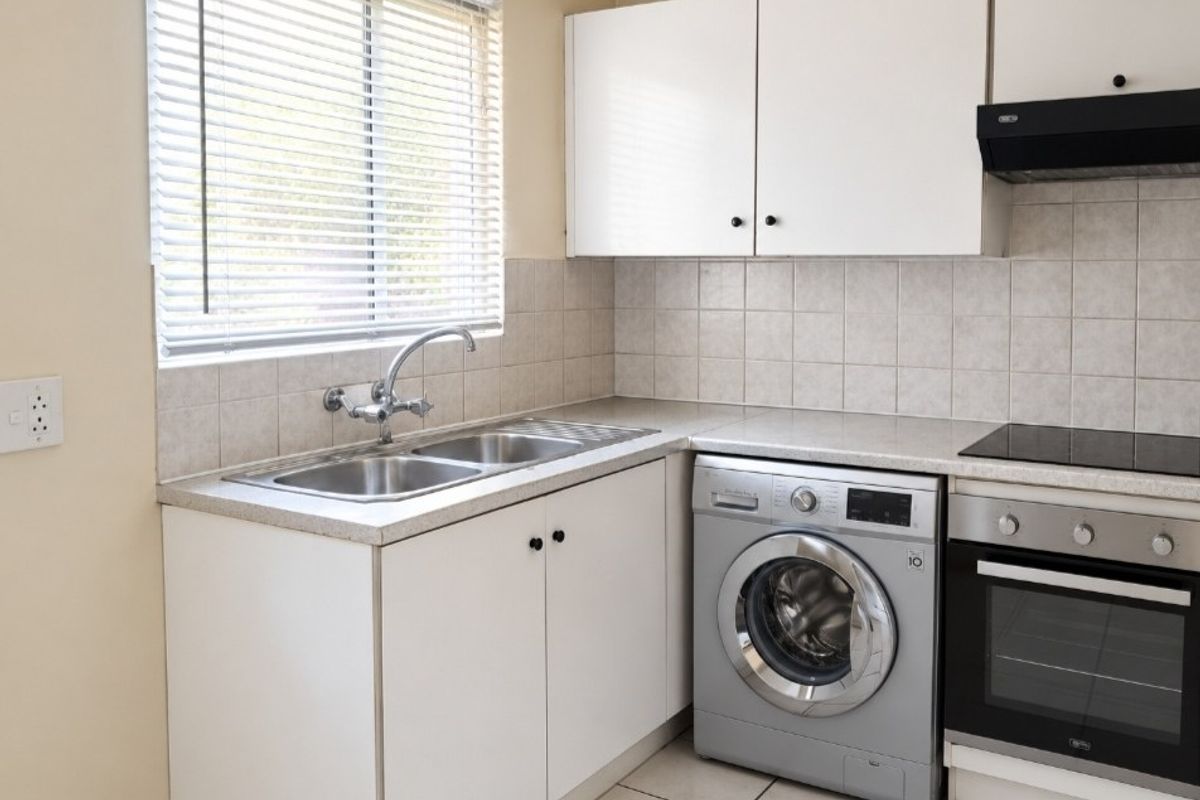 A functional kitchen featuring white cabinetry, tiled backsplash, laminate countertops, a double sink, and integrated oven with hob and extractor fan.