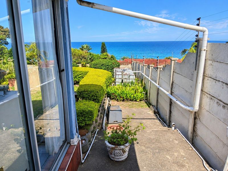 Outdoor patio area featuring a concrete surface, boundary wall with electric fencing, and direct ocean views.