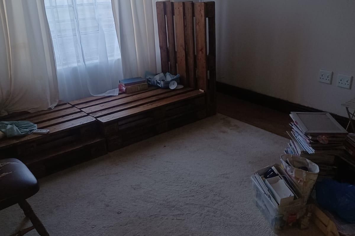 A bedroom featuring carpeted flooring, a window with security bars, and wall-mounted electrical outlets and television bracket.