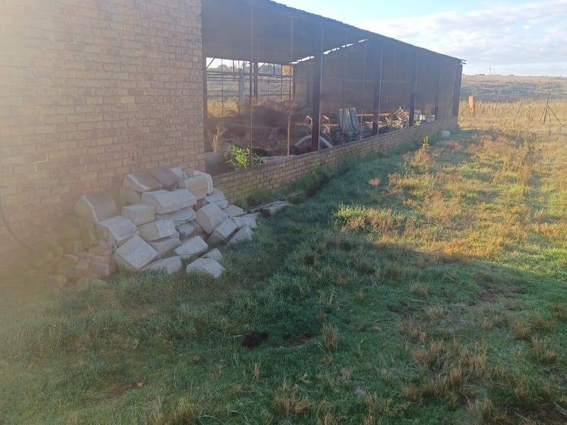 An exterior view of a dilapidated brick and metal farm shed structure requiring significant maintenance or potential demolition.