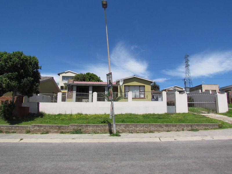 Front view of a residential property featuring a perimeter wall, metal gate, and brick retaining wall along the street frontage.