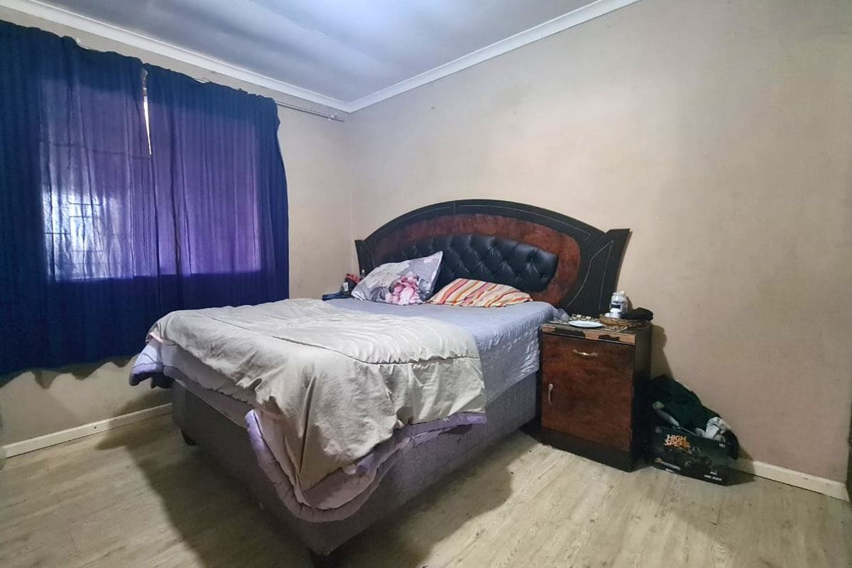 A bedroom featuring laminate flooring and coved ceilings, requiring minor cosmetic updates to the wall finishes.