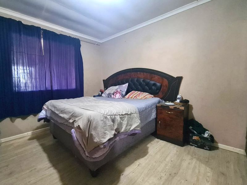A bedroom featuring laminate flooring and coved ceilings, requiring minor cosmetic updates to the wall finishes.