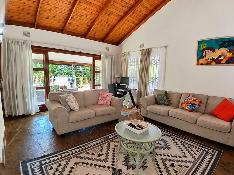 Spacious living room featuring a high vaulted timber ceiling, rustic flagstone flooring, and large sliding doors providing seamless access to the outdoor patio area.