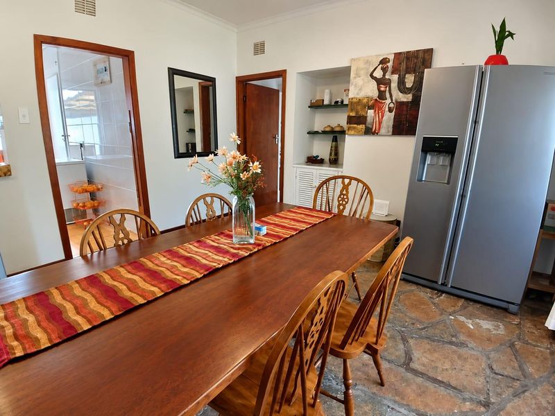 Dining room featuring rustic stone flooring, built-in shelving, and direct access to an adjacent utility area.