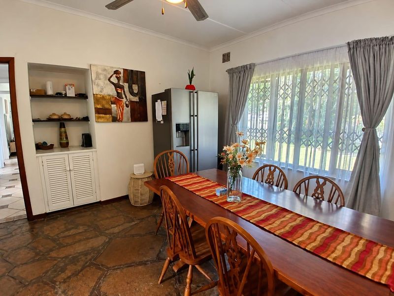 Dining room featuring natural stone flooring, built-in cabinetry with shelving, and a ceiling fan, providing a functional space for family meals.