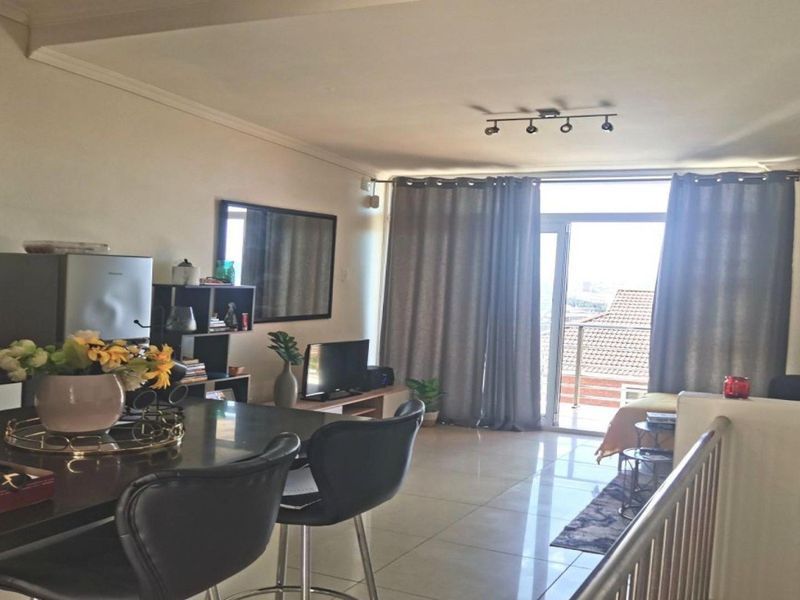 Open plan living and kitchen area featuring tiled floors, modern track lighting, and a sliding glass door leading to a balcony.