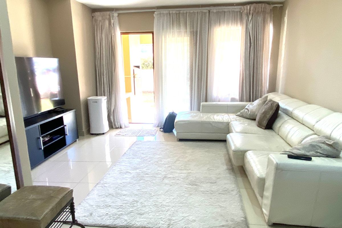 A bright living room featuring tiled flooring, recessed ceiling lights, and a sliding glass door providing access to the outdoor area.