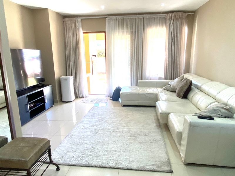 A bright living room featuring tiled flooring, recessed ceiling lights, and a sliding glass door providing access to the outdoor area.