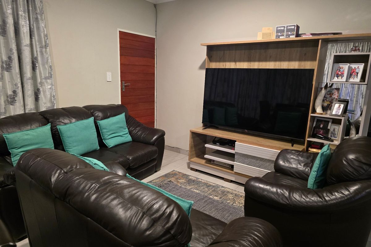 A comfortable living room featuring tiled flooring, a timber door, and decorative coving, providing a functional space for relaxation.