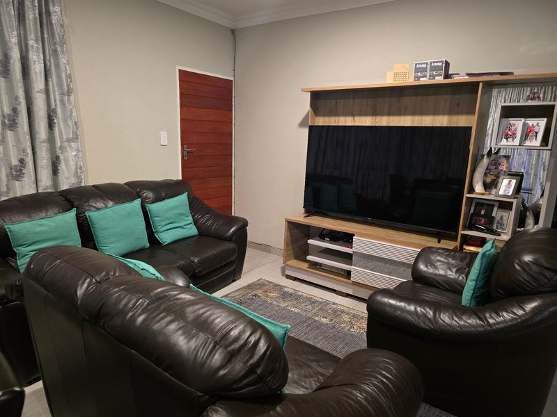 A comfortable living room featuring tiled flooring, a timber door, and decorative coving, providing a functional space for relaxation.