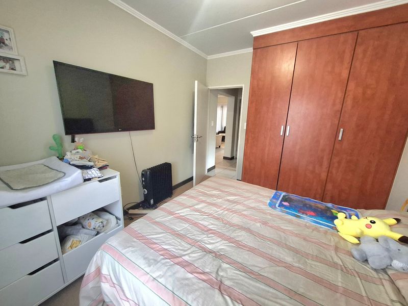 A bedroom featuring a large built-in wooden wardrobe, neutral wall finishes, and coving detail, providing functional storage space.