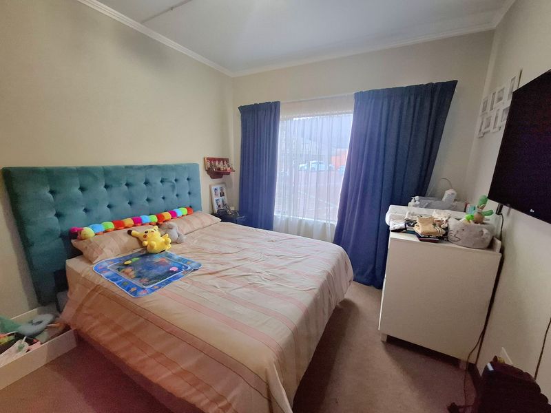 A functional bedroom featuring carpeted flooring, coved ceiling details, and a large window allowing natural light into the space.